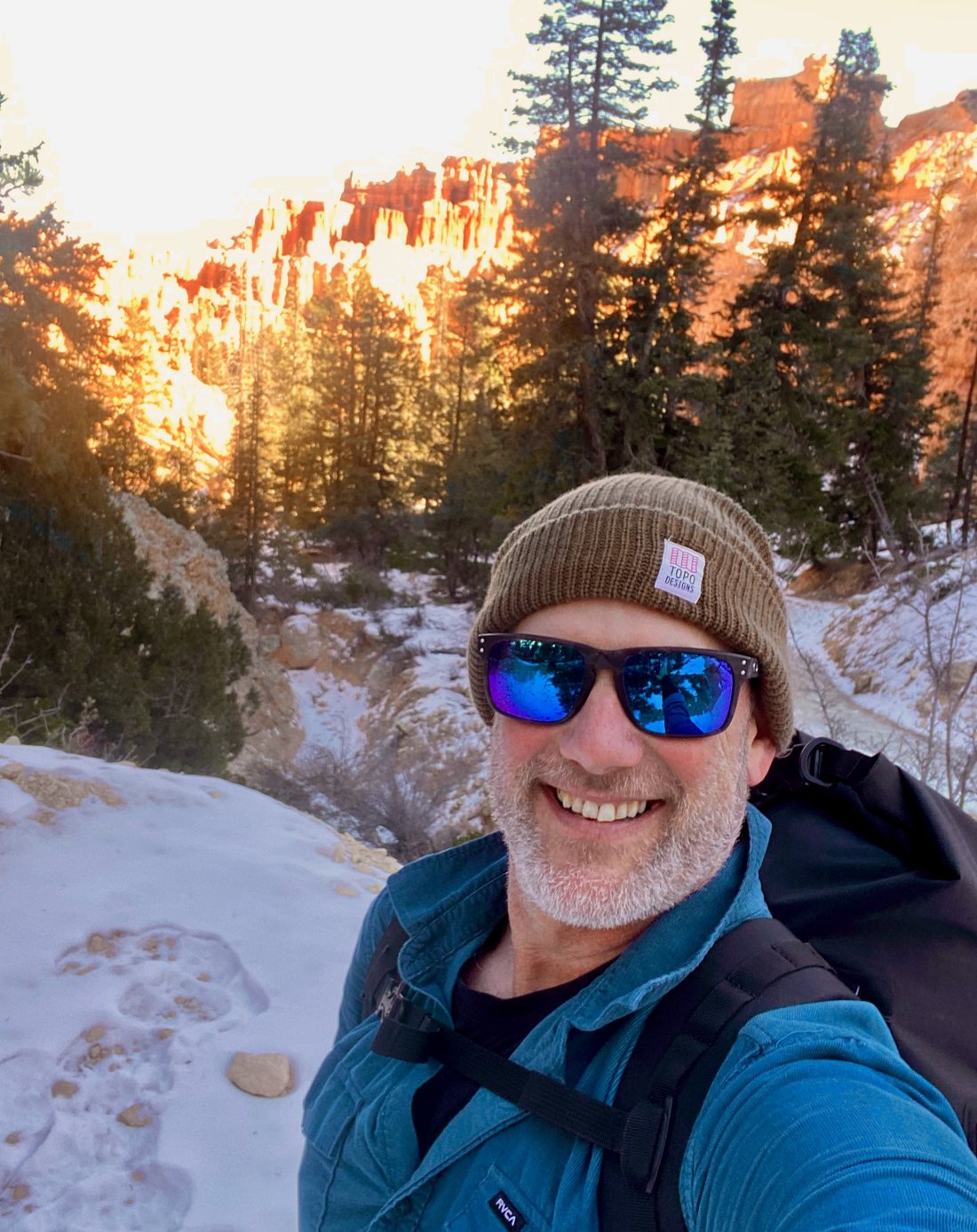 Chris Carter smiling on a snowy trail at Bryce Canyon at sunset.