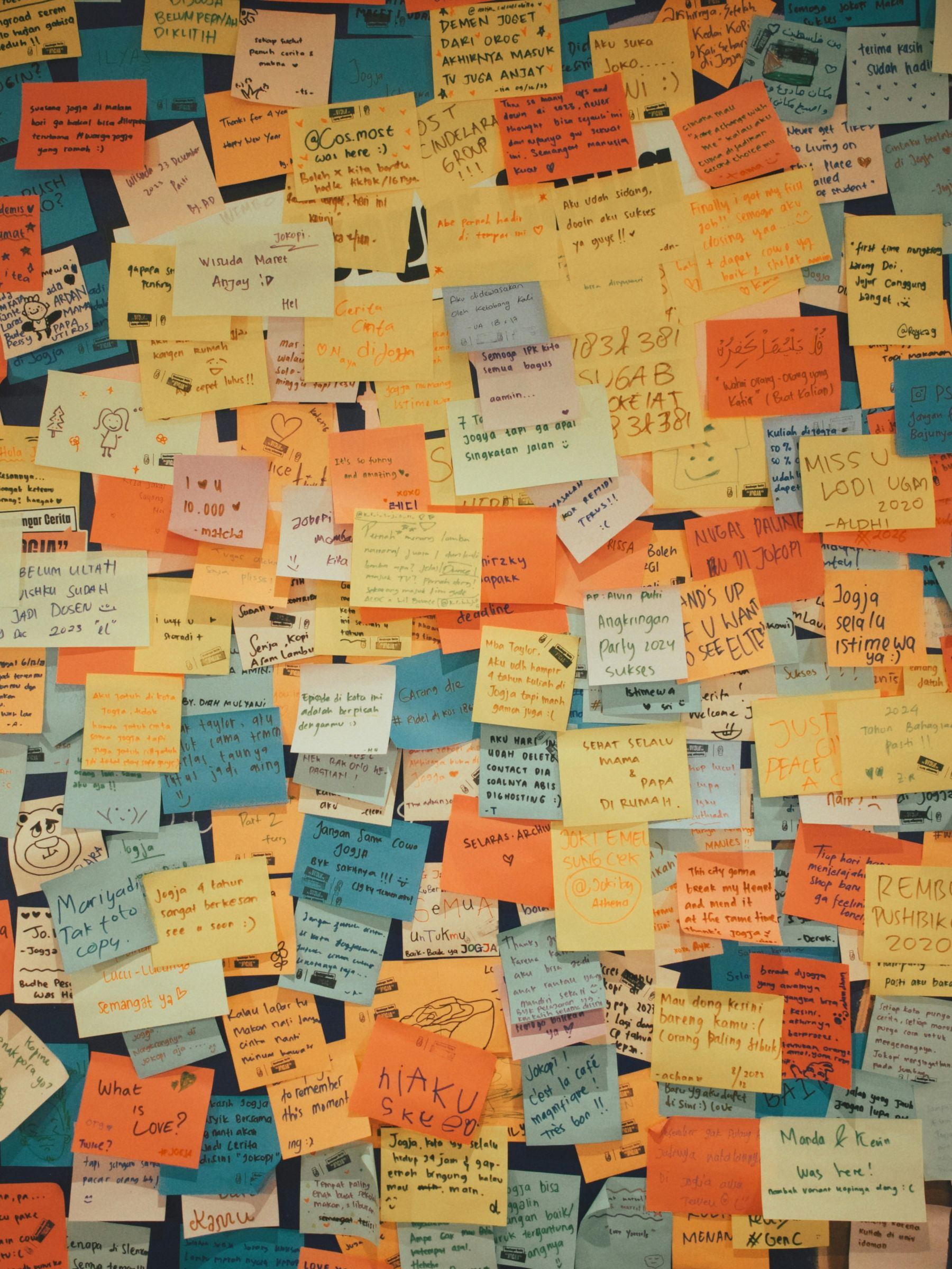 A corkboard covered in handwritten sticky notes
